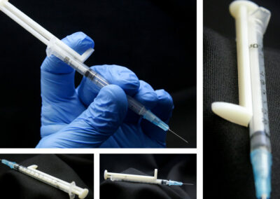 Syringe held by hand with blue protective glove